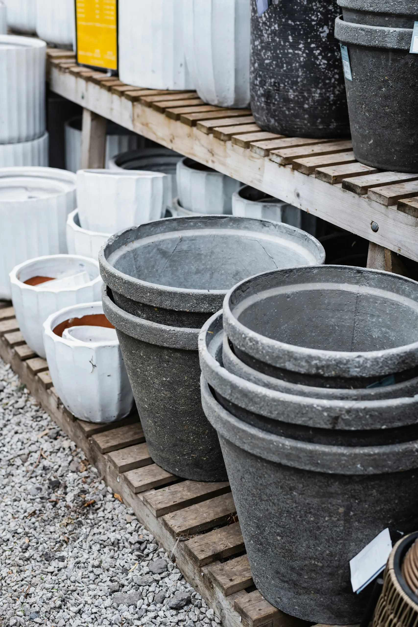 Szare i białe ceramiczne donice na drewnianych półkach